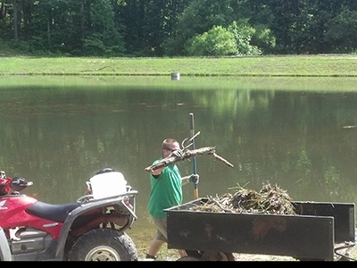 Picking up limbs, brush and organic matter along a pond's shoreline